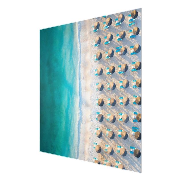 Quadri in vetro con paesaggio Spiaggia di sabbia bianca con ombrelloni di paglia