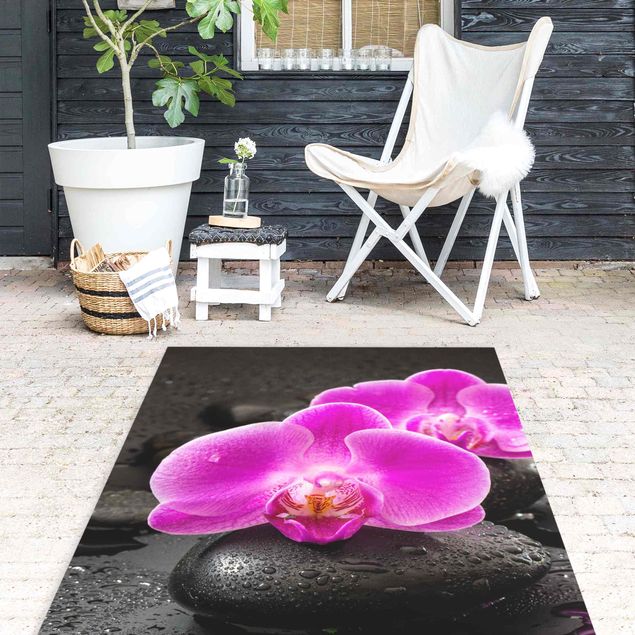 tappeto moderno Fiore di orchidea rosa su pietra con gocce